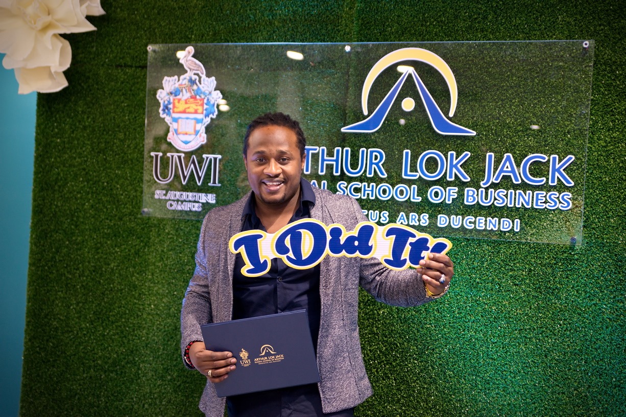 Graduate holding a certificate at the UWI-ALJGSB backdrop