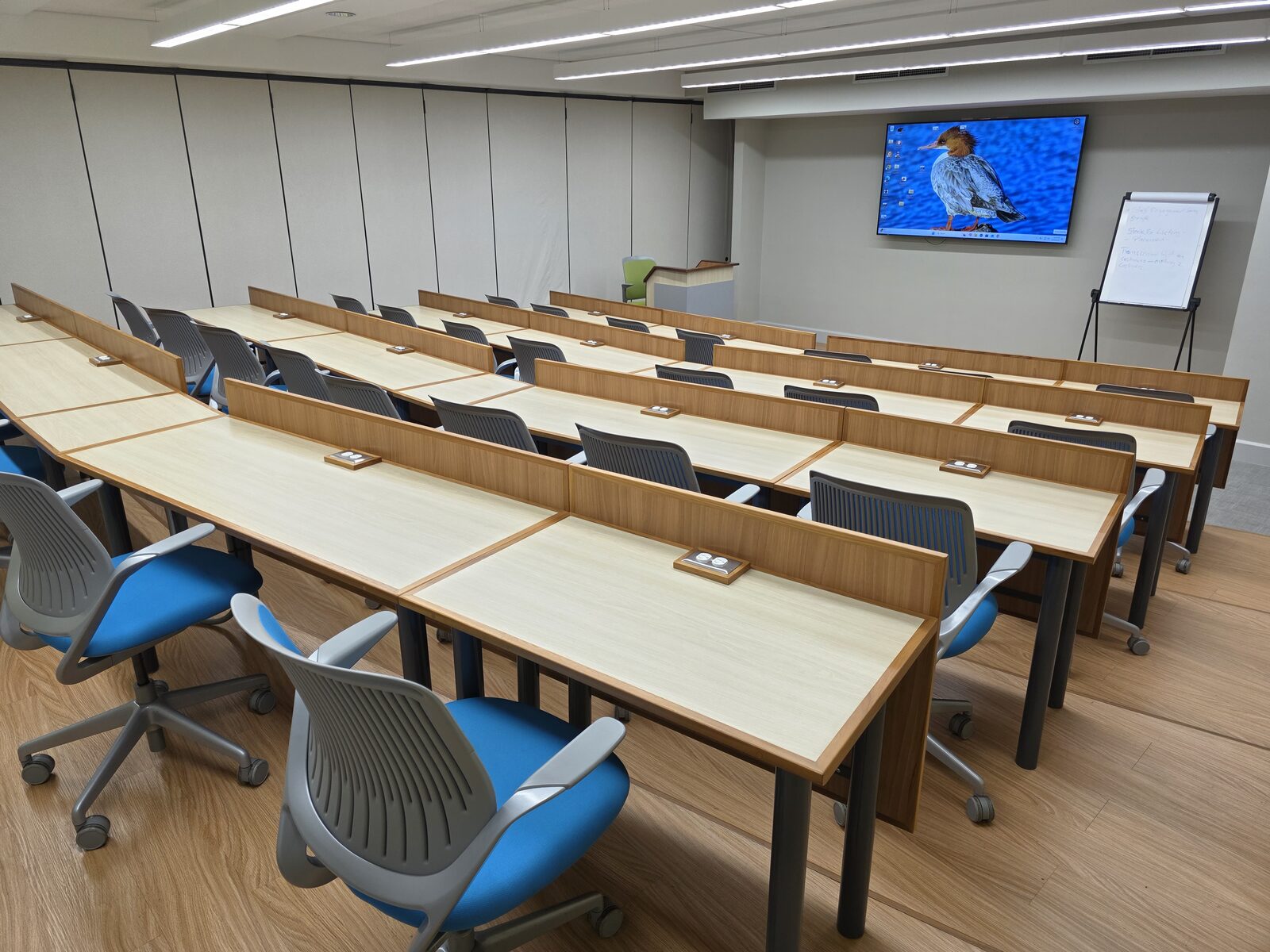 Lecture Room 1 - curved desks with blue swivel chairs and power outlets