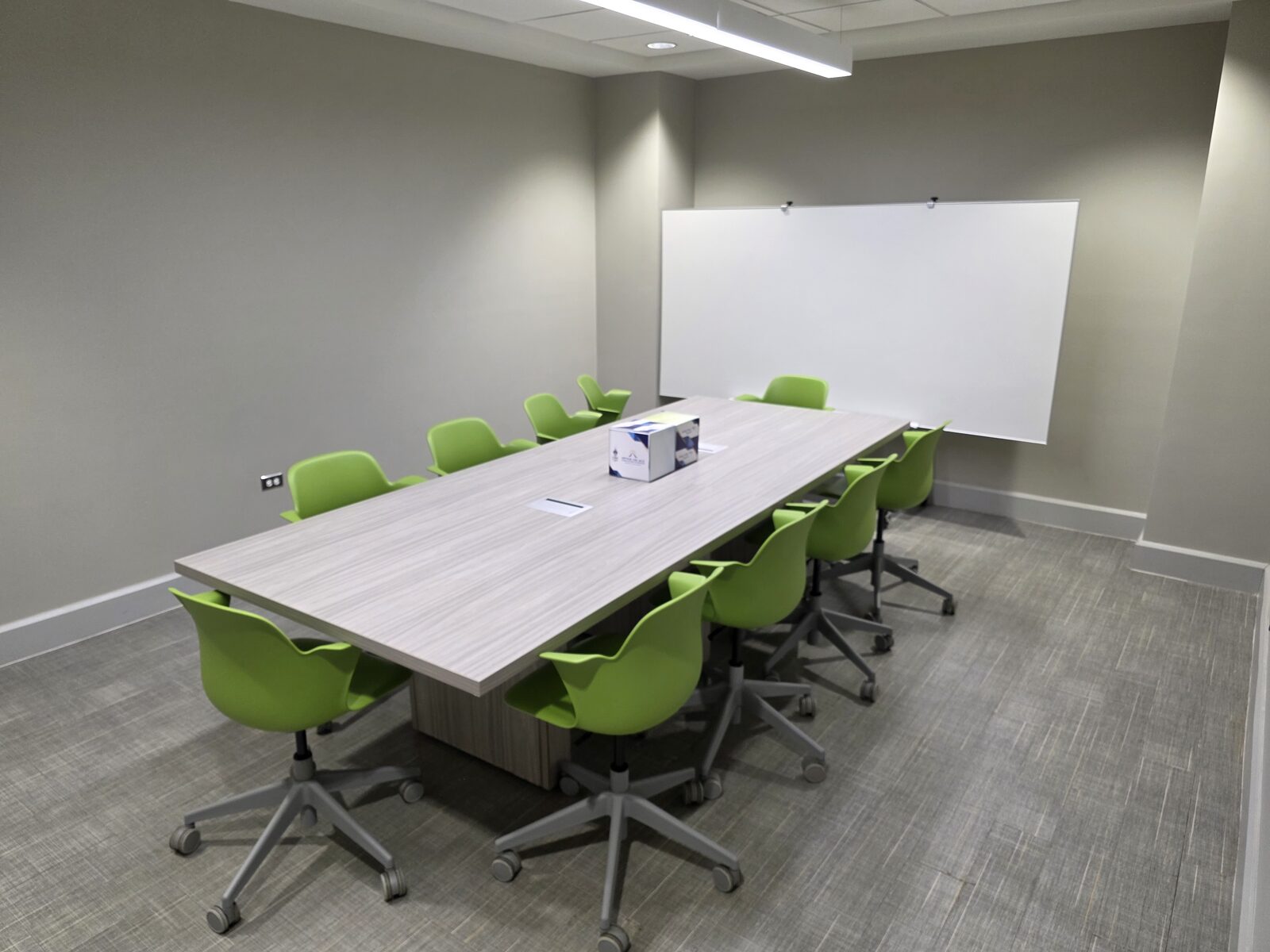New Wing Small Meeting Room - a boardroom table with ten chairs and a whiteboard